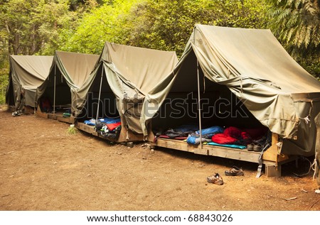 A series of basic canvas tents on wooden tent platforms at a Boy Scout camp provide the basics for shelter and not much more. Royalty-Free Stock Photo #68843026