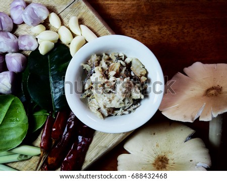 Top view picture of the ingredient for spicy fish curry sauce on wooden consist of shallot, garlic, dried chili, lemon grass, kaffir lime leaves, fish meat and  mushroom.