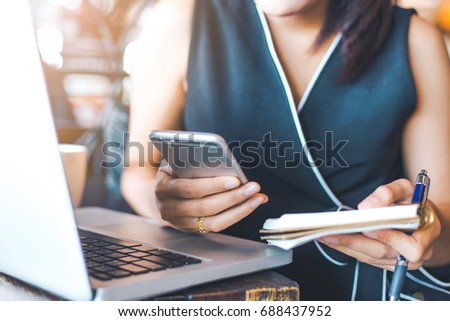 Businesswoman working in office,She holds a cell phone and notepad.