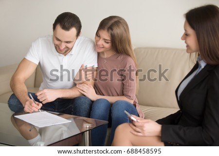Cheerful couple signing documents on meeting with female realtor, notary or lawyer, young man putting signature, banker approving loan, mortgage investment, prenuptial agreement, sale purchase deal Royalty-Free Stock Photo #688458595