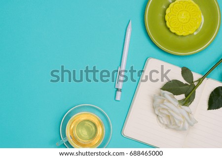 Snow skin mooncake and tea cup with flowers on dark background. Open notebook with copy-space.
