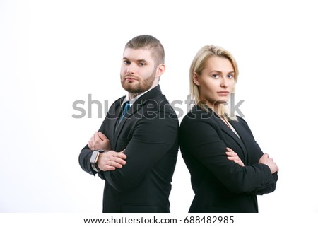 Serious business colleagues stand with hands clasped on chest with back to each other and look at camera standing on white isolated background