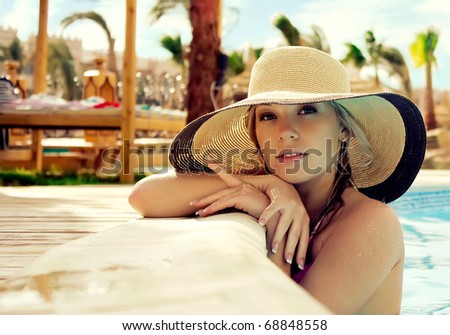 The smart blonde in a hat in pool of expensive hotel