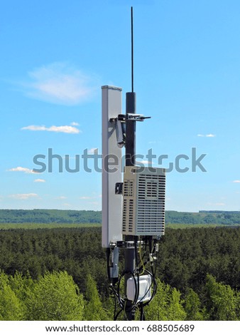 Cell phone antenna on the roof of the building, transmitter. Telecom radio mobile microwave antenna against blue sky 