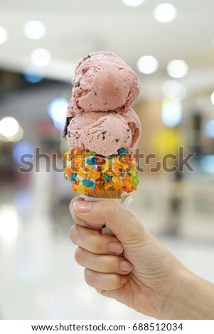 Hand holding Fantasy Cone of Ice cream, Blueberry Sherbet and Raspberry Sorbet on blurred background, Enjoy eating in the summer day.