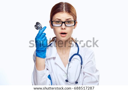 Woman doctor wearing glasses and a medical gown holding a stethoscope working in a hospital, medicine                               