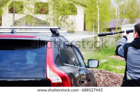 A man washes his car in the yard