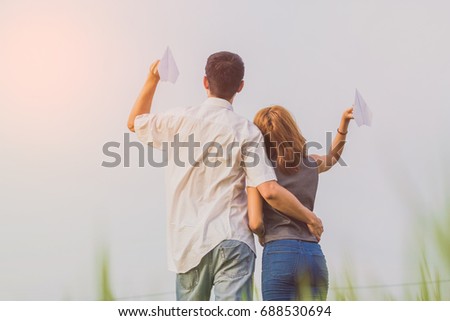 Two paper airplanes in hands looking at each other at park