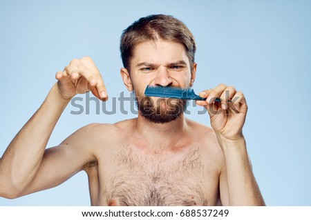 Man combing his beard on a blue background                               