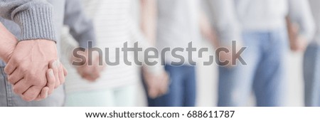 Group therapy patients standing and holding hands during session Royalty-Free Stock Photo #688611787