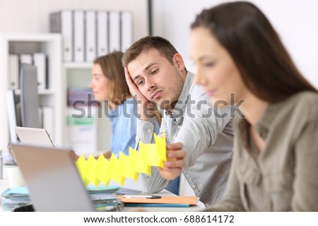 Portrait of a lazy employee boring sitting in a desktop between other workers at office Royalty-Free Stock Photo #688614172