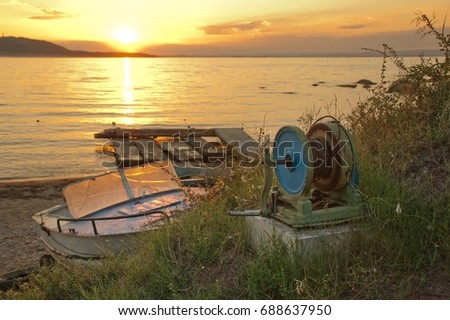 Seascape with pulley for dragging fisher boat on the beach against beautiful sunset above the sea water. Summer romantic concept.