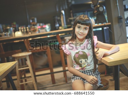 Asian thai children with glasses are about to read a book in a coffee shop.