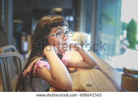 Asian thai children with glasses are about to read a book in a coffee shop.