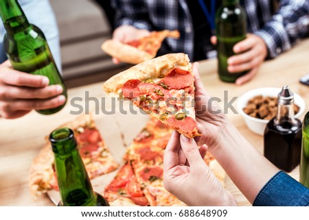 cropped shot of friends eating pizza together at home