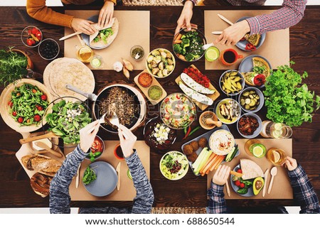 Friends meeting at a vegan dinner with hummus, falafels and vegetables Royalty-Free Stock Photo #688650544