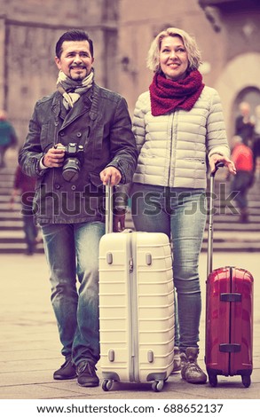 Elderly couple of travellers with baggage going to hotel