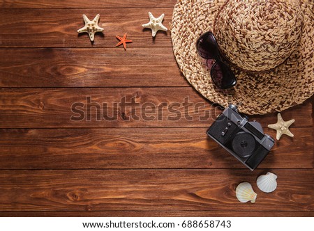 photo camera retro hat sunglasses and seashells border on wooden background