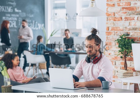 Young man working on his laptop in co-creative space Royalty-Free Stock Photo #688678765