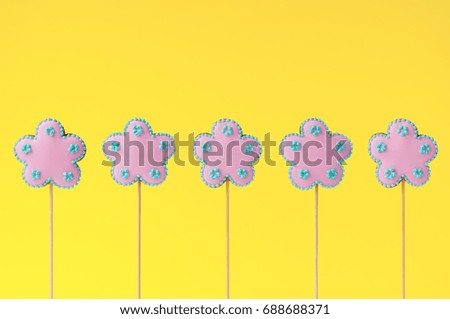 Topper. Row of homemade gingerbreads in the form of pink flowers on the yellow background. Picture for a menu or a confectionery catalog. Invitation or greeting card.