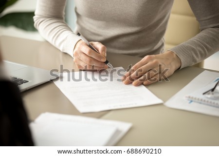Woman signing document, focus on female hand holding pen, putting signature at official paper, subscribing name in statement with legal value, contract management, good business deal, close up view Royalty-Free Stock Photo #688690210