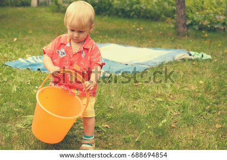Little girl is playing with an empty bucket