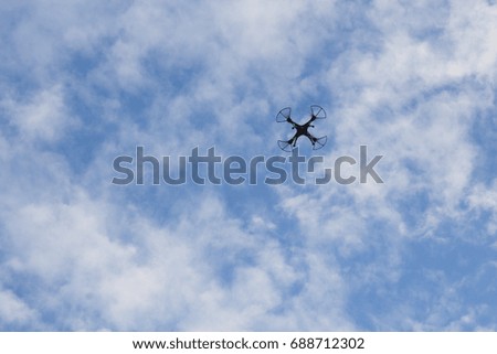 Flight of Drone in Blue sky. View of remote Quadcopter from Earth.