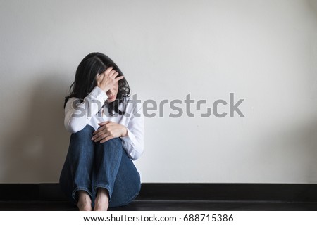 Stressful depressed sad woman with mental health illness, headache, migraine and emotional anxiety, dizziness, panic disorder, or cervical vertigo symptom sitting on the floor  in home living room  Royalty-Free Stock Photo #688715386