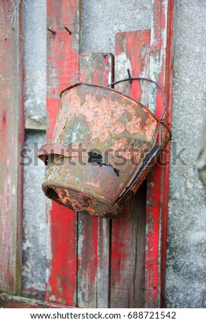 Firefighter shield with an old, rusty, leaky bucket. Abandoned garden plot. Rural landscape.