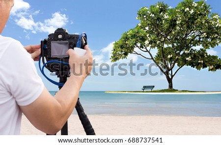 Photographer taking picture of the beach with frangipani tree with dslr camera