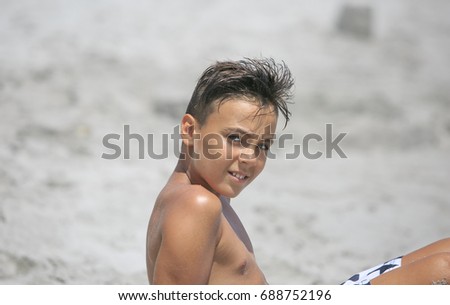 Boy with beautiful green eyes looking at the camera on the beach