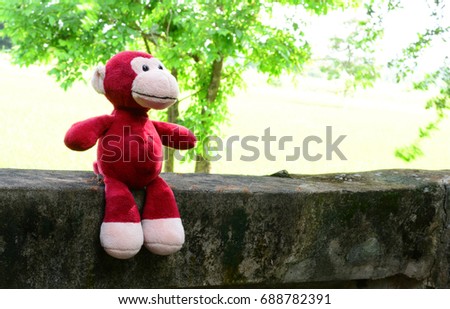 red monkey doll lonely  at old wall