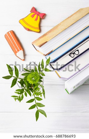 Hello, September, hello autumn! Books, bookmark glasses, gingerbread (pencil and yellow bell), green chrysanthemum on a white wooden background. Top view