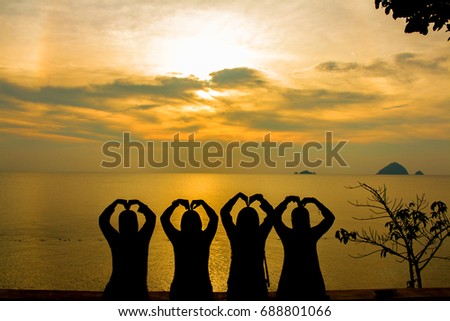 Silhouette of many friends watching sunset and make a hand gesture. soft focus due to silhoutte.visible noise due to high iso