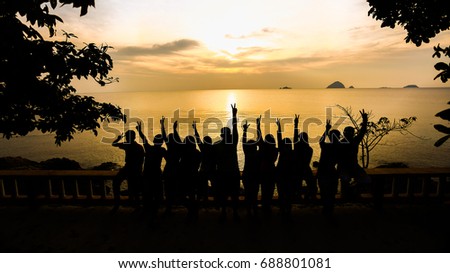 Silhouette of many friends watching sunset and make a hand gesture. soft focus due to silhoutte.visible noise due to high iso