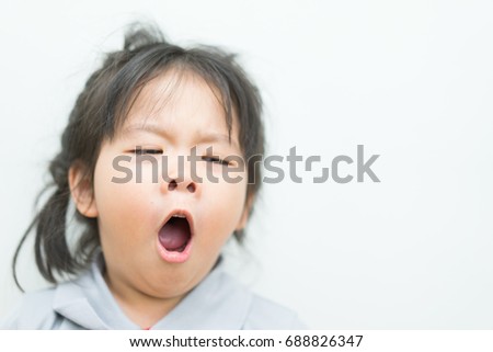 Little asian girl yawning on a white background.