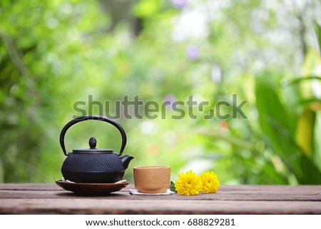 Old black tea pot with brown cup and flower