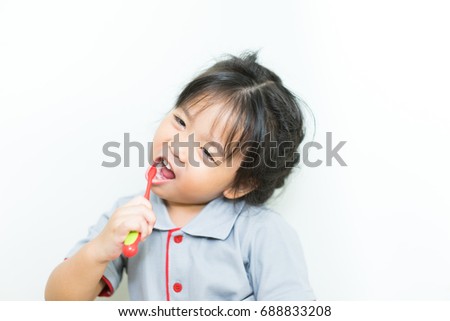 Toddler smiling while brushing her teeth.Little beautiful asian girl brushing teeth, healthy concept.