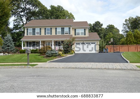 Beige Suburban high ranch home with two car garage and blacktop driveway USA Royalty-Free Stock Photo #688833877