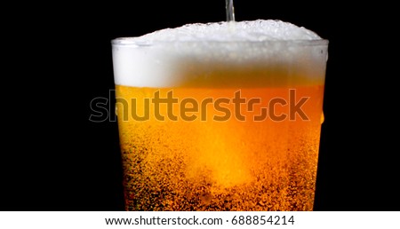 Pouring lager beer on a pint glass with black background Royalty-Free Stock Photo #688854214