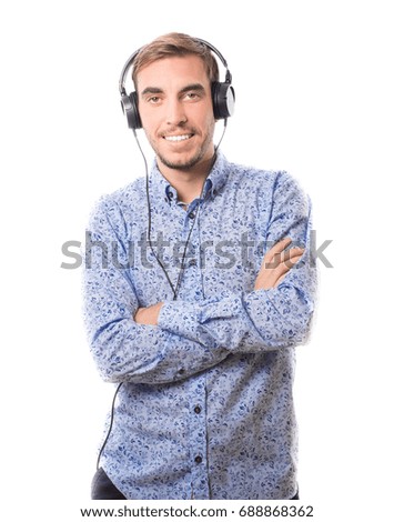 Smiling young man listening to music with headphones and keeping arms crossed isolated on white background