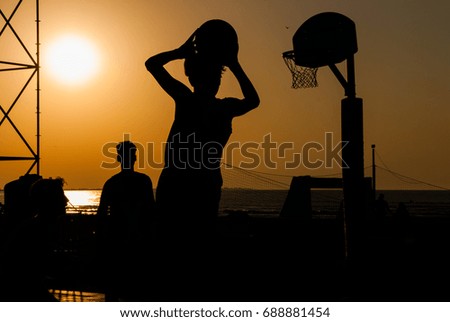 Street basket players in front of the sea at sunset
