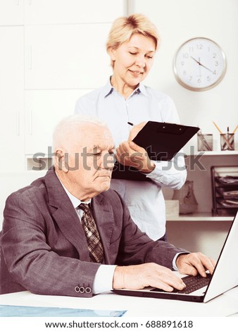 Aged manager and secretary working productively together in office