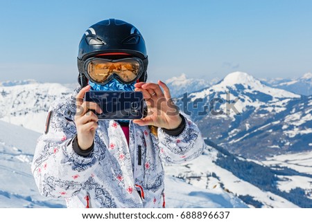 Young skier woman taking photo with the smartphone