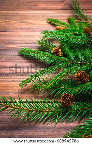 Christmas-tree branches with cones on a wooden background.