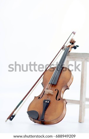 Vintage Violin leaned by a stool on a white background