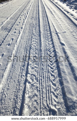 the trace of the wheels of the car on the snow-covered road. Photographed close-up.
