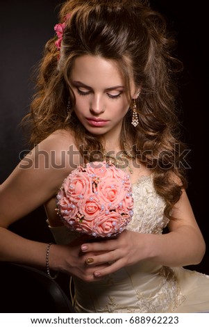 Beautiful bride posing on camera and holding a bouquet in a wedding dress on a black background