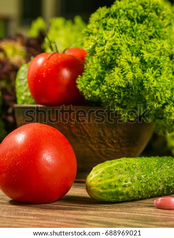 Fresh vegetables. Tomatoes and cucumbers on a wooden table. Green salad in the background. Healthy food,dieting concept.