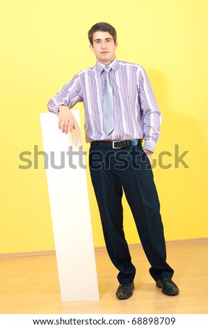 full length portrait of a attractive young businessman leaning on empty sheet against uniform background